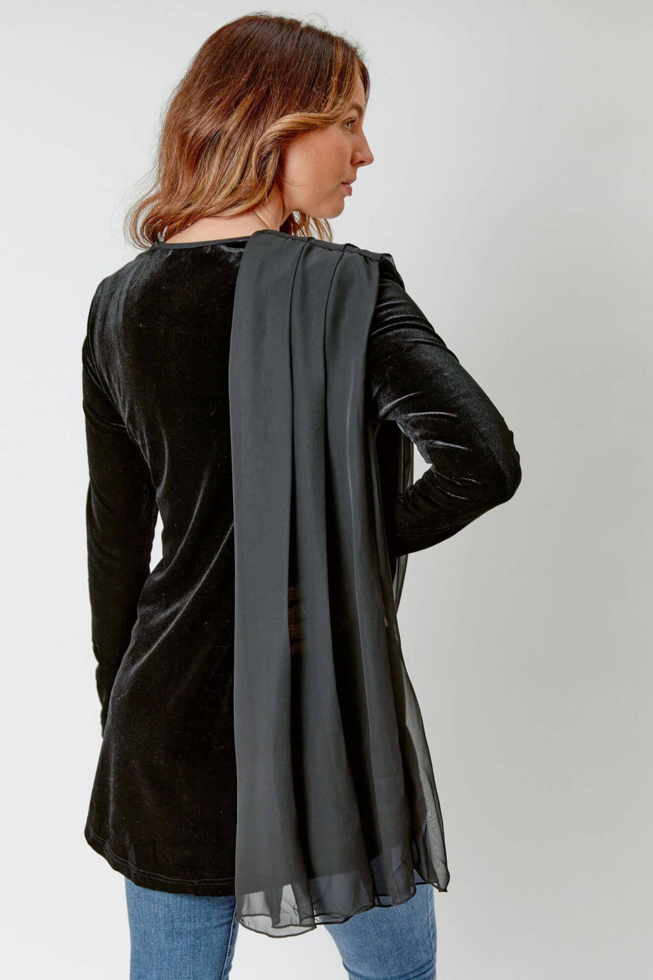 Woman wearing a black cardigan with a sheer overlay on a white background