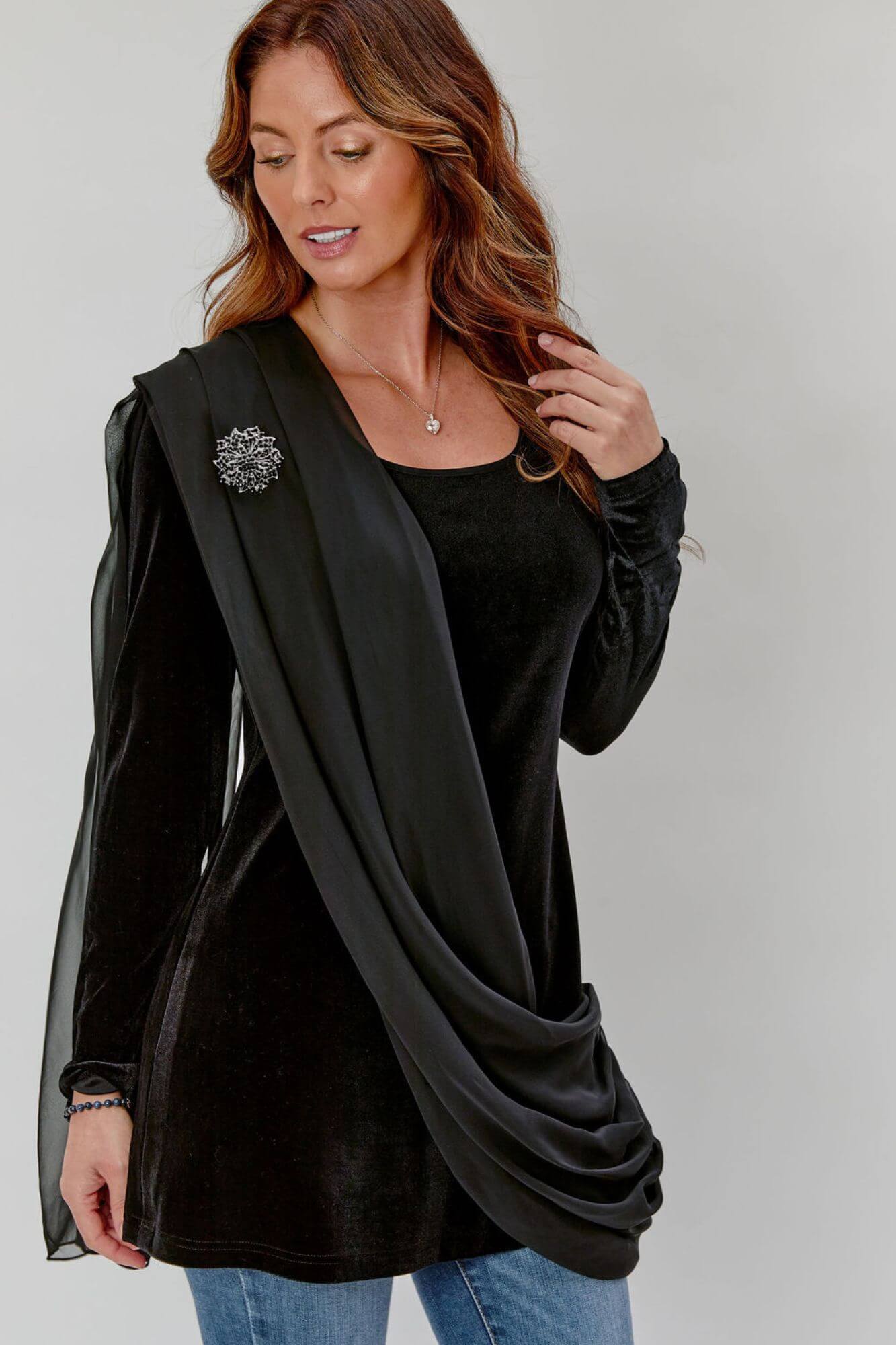 Woman wearing a black cardigan over a black top with a plain background