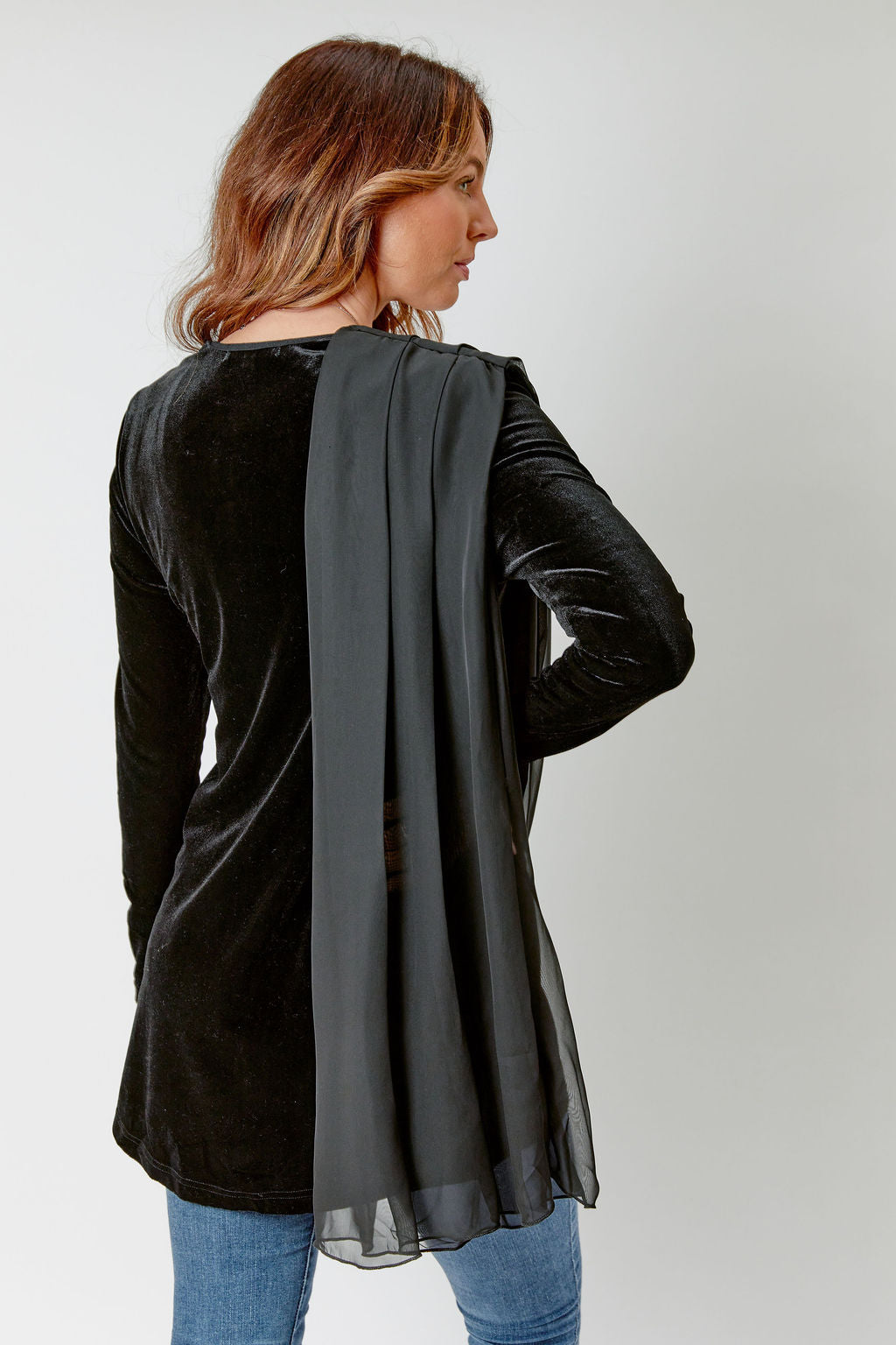 Woman wearing a black long-sleeve top with sheer overlay on a white background